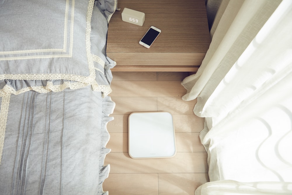 smartphone na mesa lateral marrom ao lado da cama