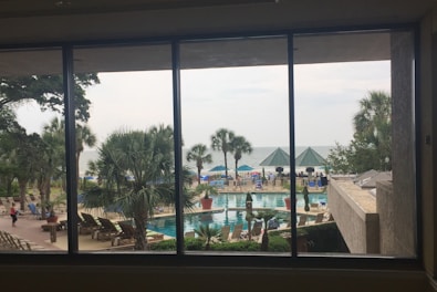 A luxurious hotel suite with a large window overlooking a tropical landscape.