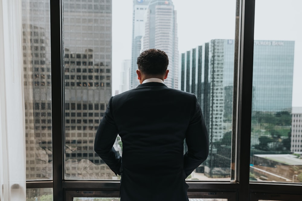 man putting hands on pocket while standing in front of glass wall