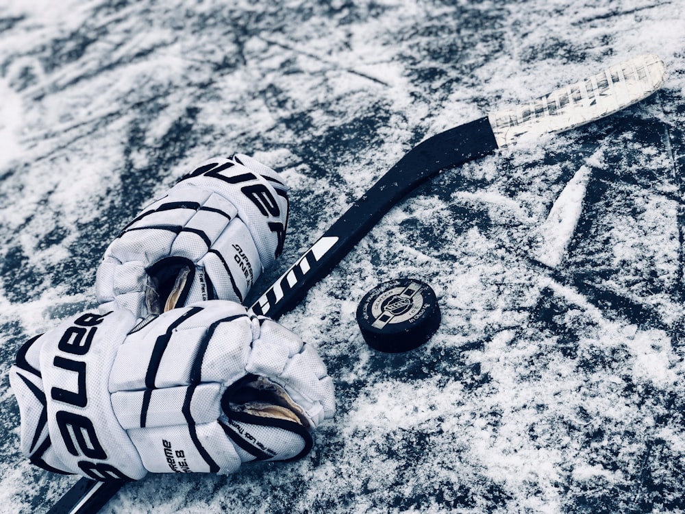 Schwarzes Eishockey neben Handschuhen