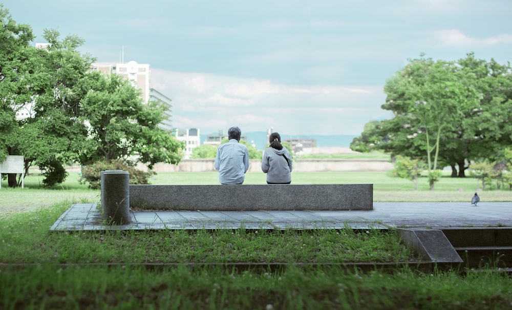 two person sitting on concrete bench