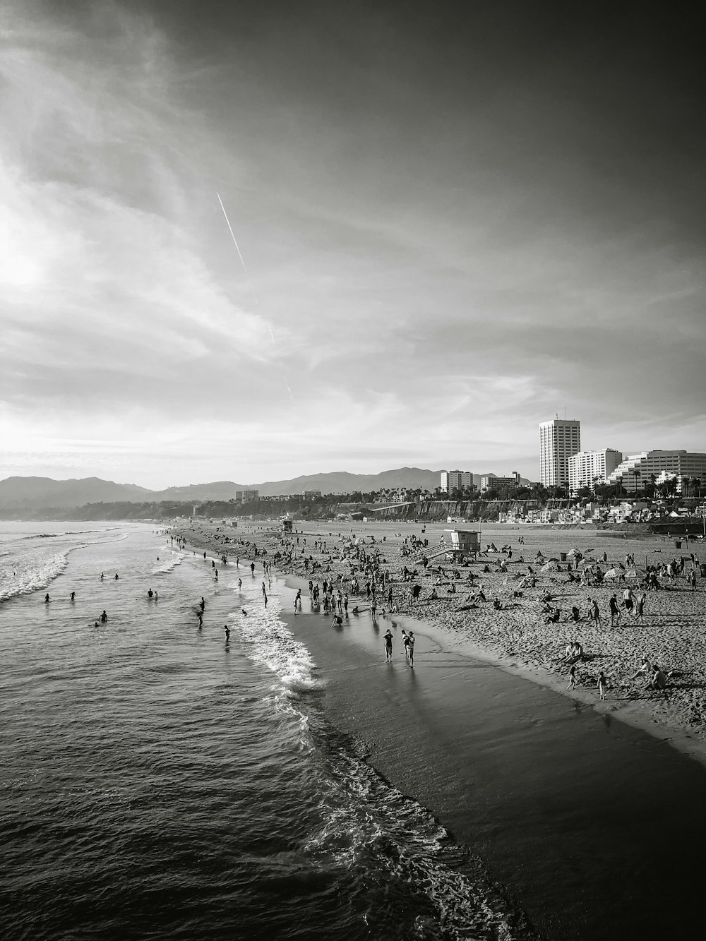 fotografia em tons de cinza de pessoas reunidas perto da costa