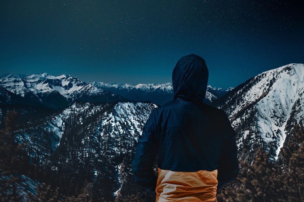 person wearing jacket facing mountains