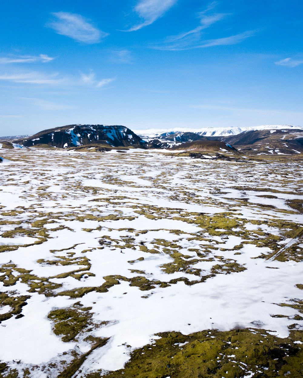 photography of green grass field cover by snow at daytime