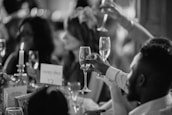 grayscale photo of people rising a drinking glasses