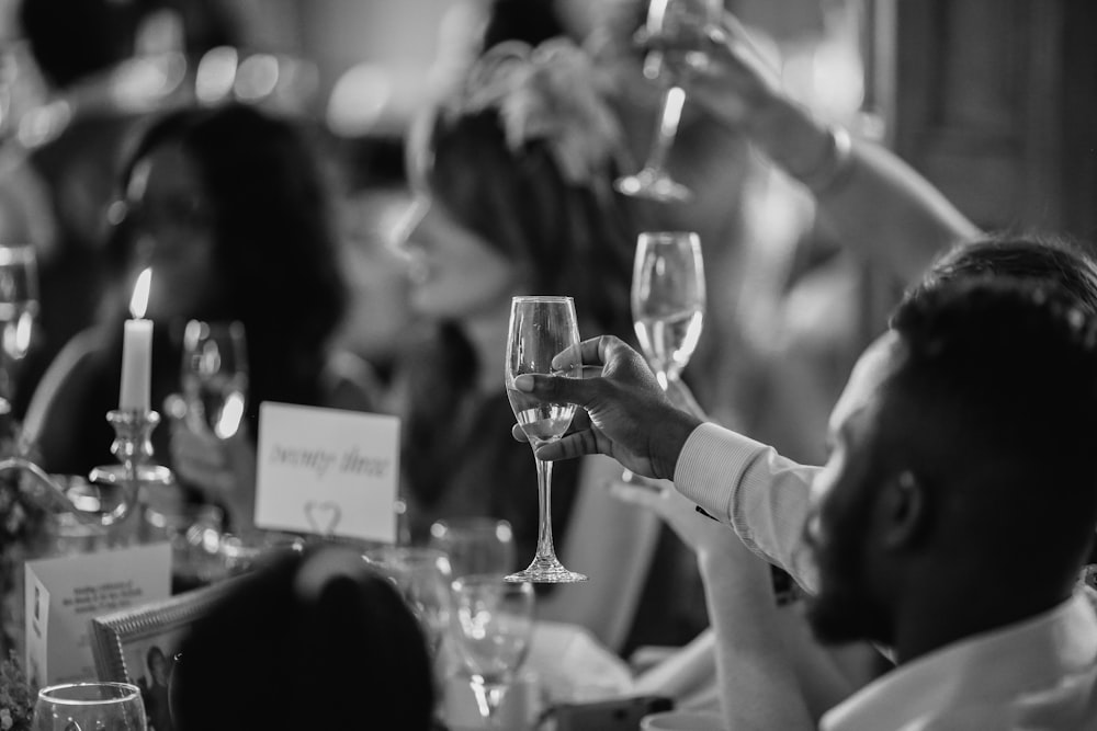 grayscale photo of people rising a drinking glasses