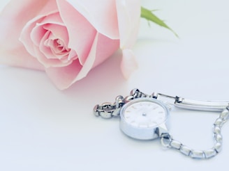 Soft pink Timely Grace watch resting on a light fabric background, highlighting its gentle hue.