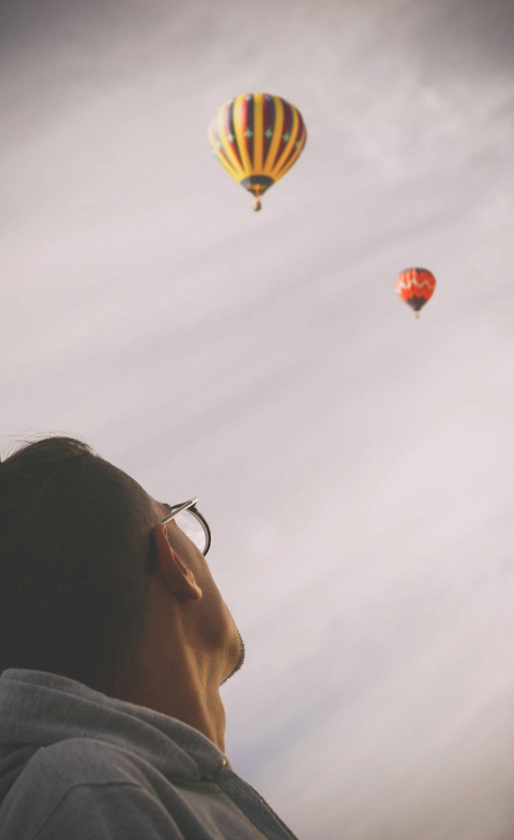 Mann schaut auf zwei Heißluftballons am Himmel