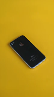 Close-up of a sleek black iPhone with yellow accents on a dark background