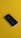 A black smartphone is resting on a bright yellow surface. The phone's back features a prominent silver apple logo, and its design is sleek and minimalist.