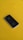 A black smartphone is resting on a bright yellow surface. The phone's back features a prominent silver apple logo, and its design is sleek and minimalist.