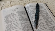 An open book with spiritual texts and a feather pen.