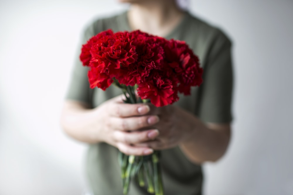 selective focus photography of person holding red rose bouquet