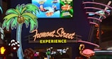 Colorful neon signs featuring a large palm tree, a flamingo, and dice prominently displayed. Above, an advertisement shows people ziplining with vibrant colors. The iconic 'Fremont Street Experience' sign is illuminated in bright lettering.