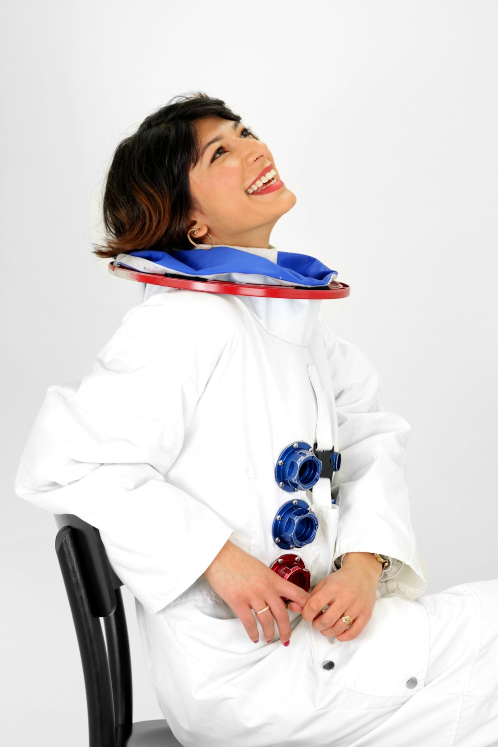 woman wearing astronaut suit smiling while sitting on chair and looking up