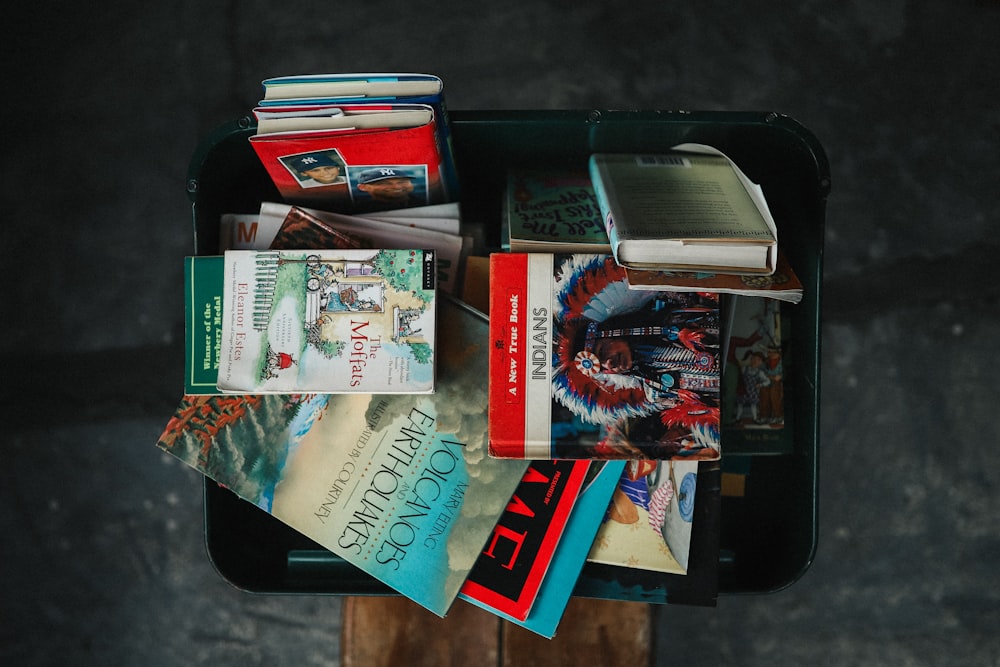 assorted books in black storage box in top view photography