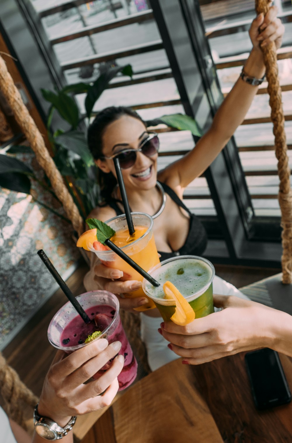 three persons raising her hand holding plastic cups