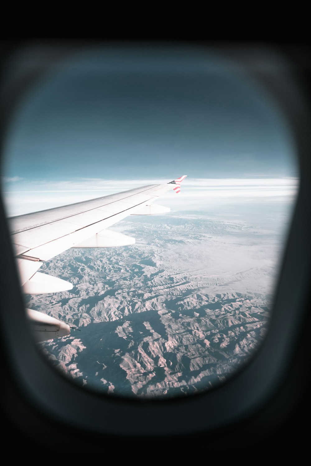 낮 동안 비행기의 날개와 산의 비행기 창문 보기