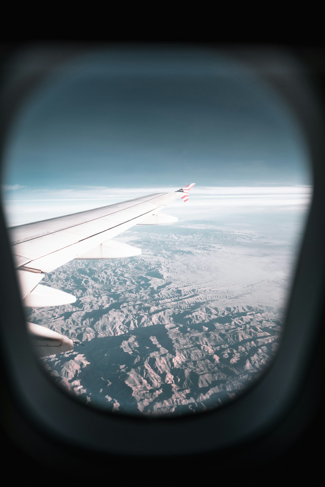 airplane window view of airplane's wing and mountains during day