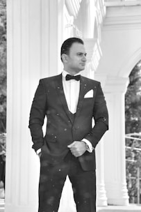 A stylish young man wearing a tailored black suit at a graduation event.