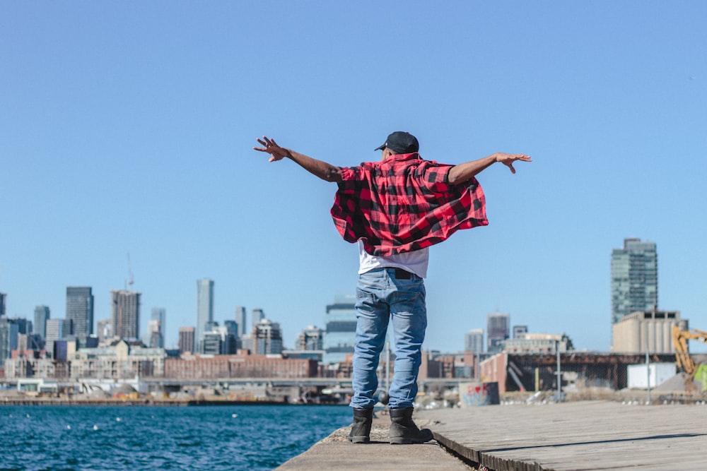 man spreading his arms while standing beside sea