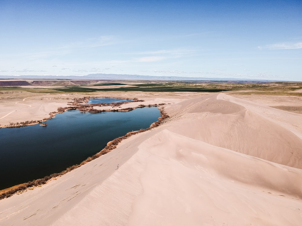 desert beside body of water during day time