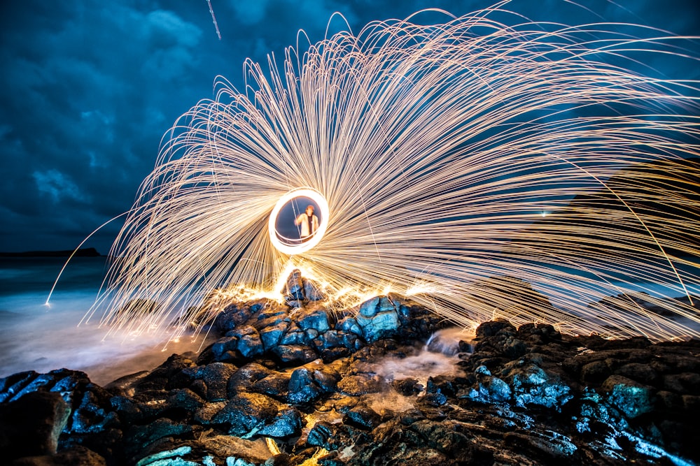 steel wool photo of man standing on rack while performing fire dance
