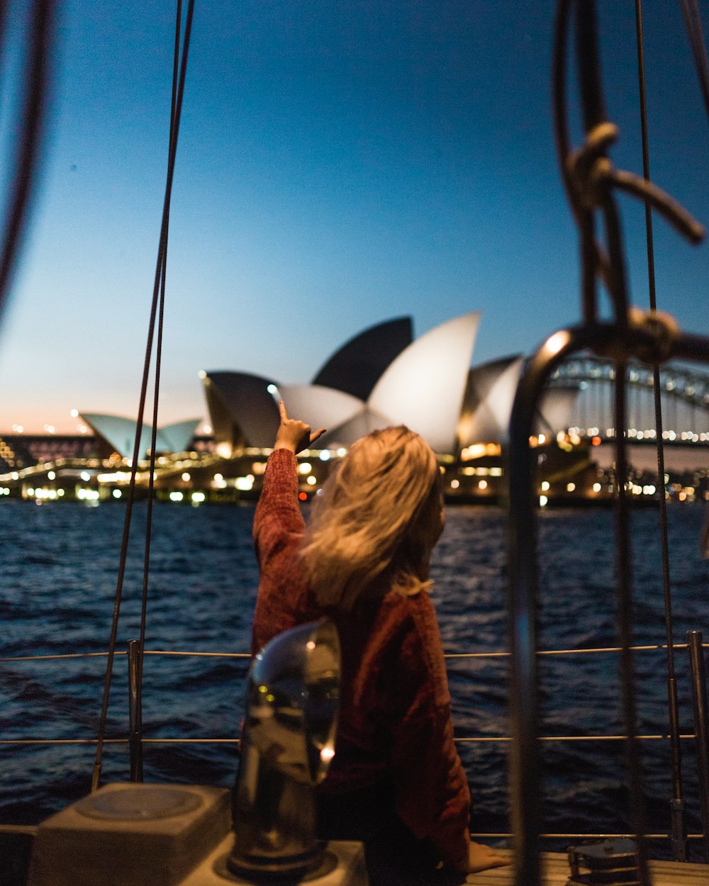 シドニーオペラハウスを眺めるボートの上に立つ女性