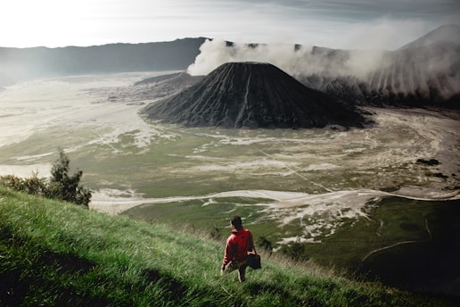 person standing on grass field near mountain