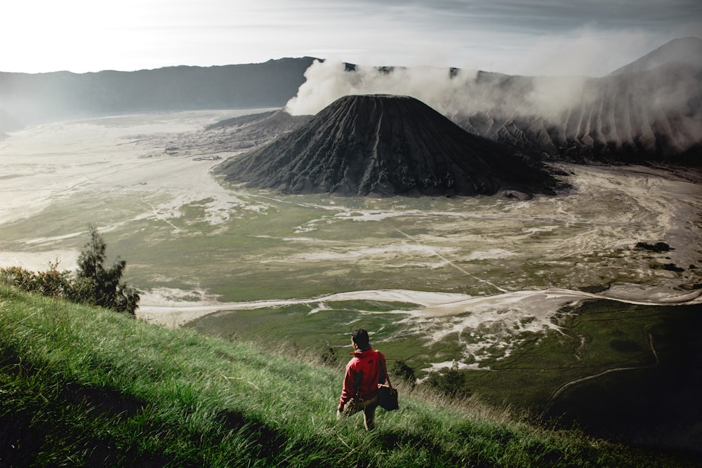 person standing on grass field near mountain