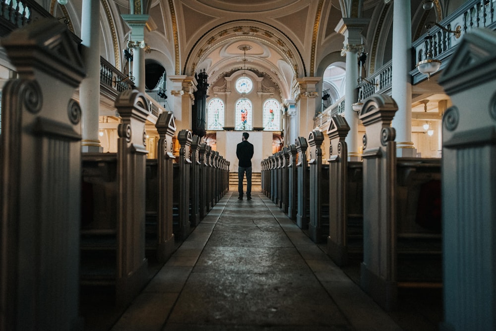 homme debout entre les bancs de l’église