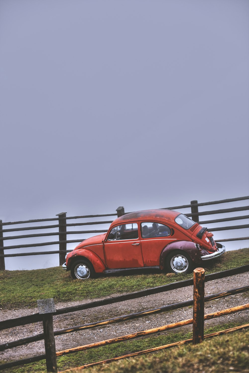 Coccinelle Volkswagen rouge à côté d’un rail en bois