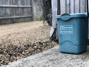 green trash can beside wooden fence