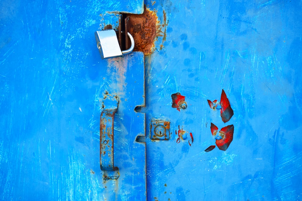 silver padlock on blue steel door