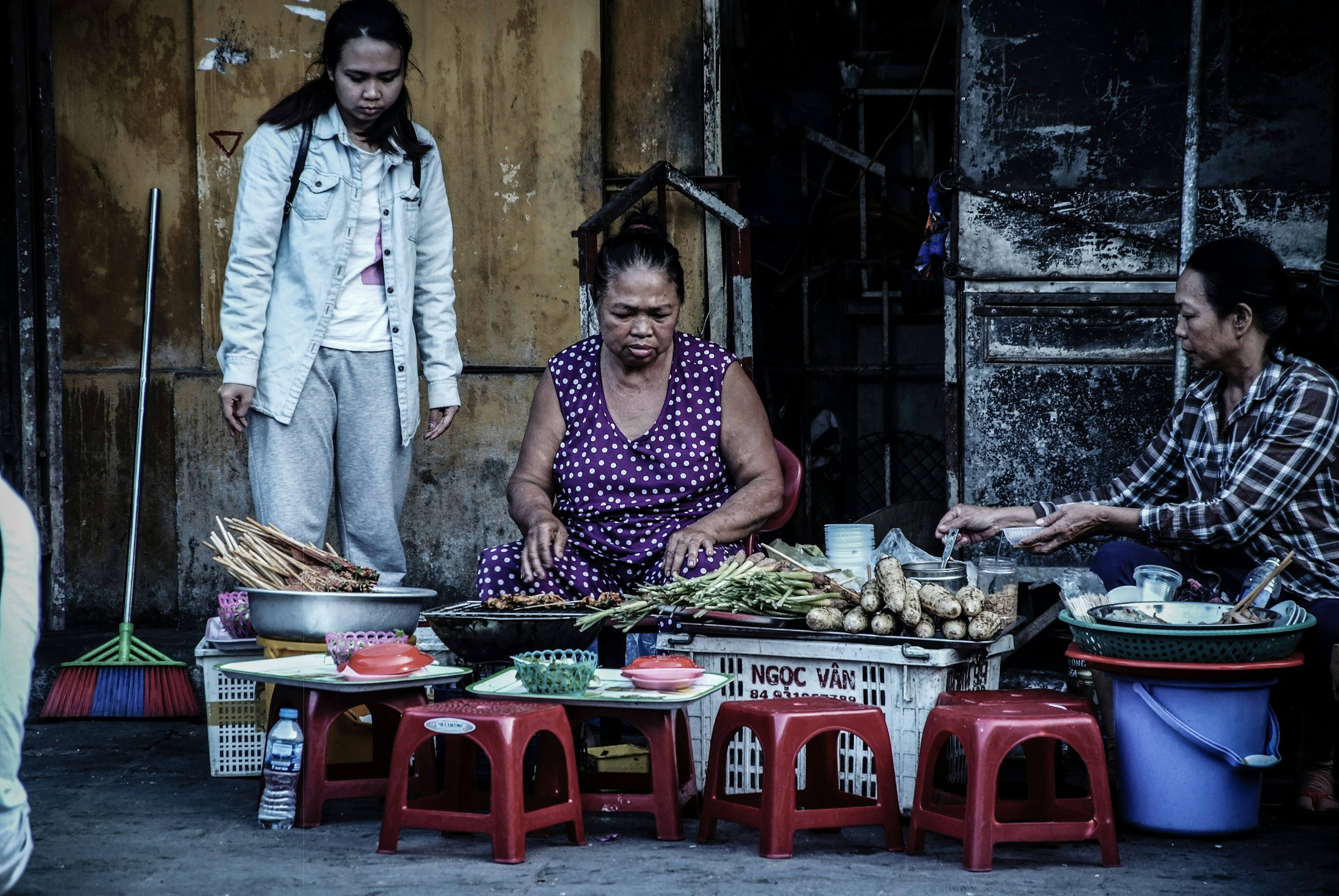 woman sitting in front vegetables beside two women
