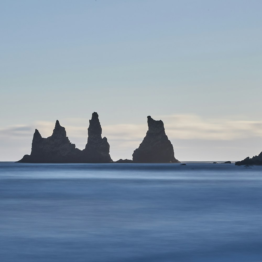 silhouette of rock formation on sea