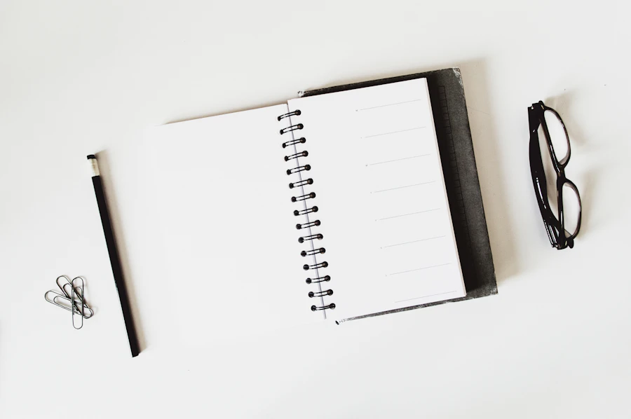 Open spiral notebook with a pencil and paper clips on a white desk
