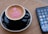 A close-up of a smartphone displaying customer reviews with a cup of coffee beside it.