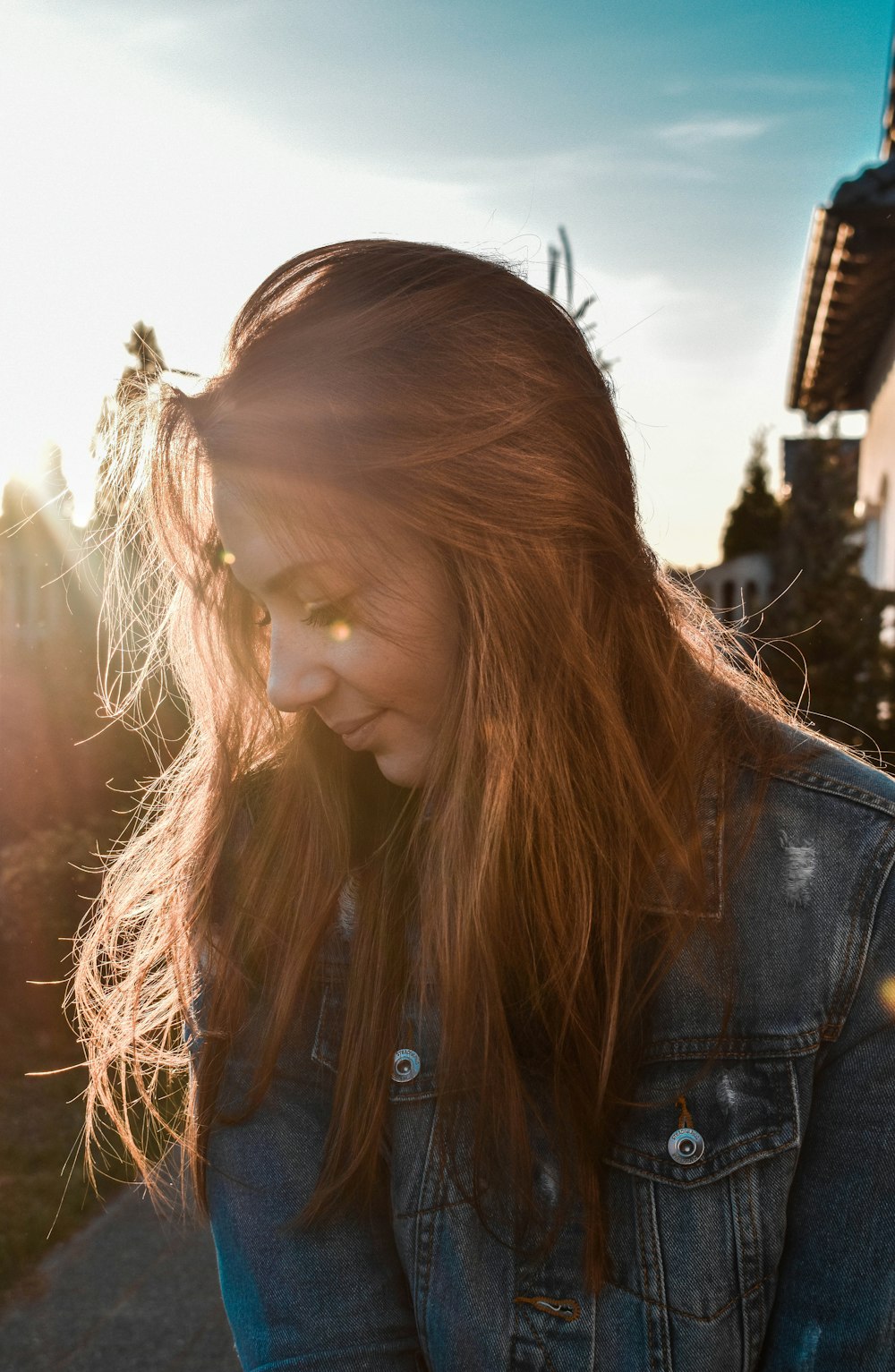 woman wearing blue denim jacket looking on her right side in shallow focus photography