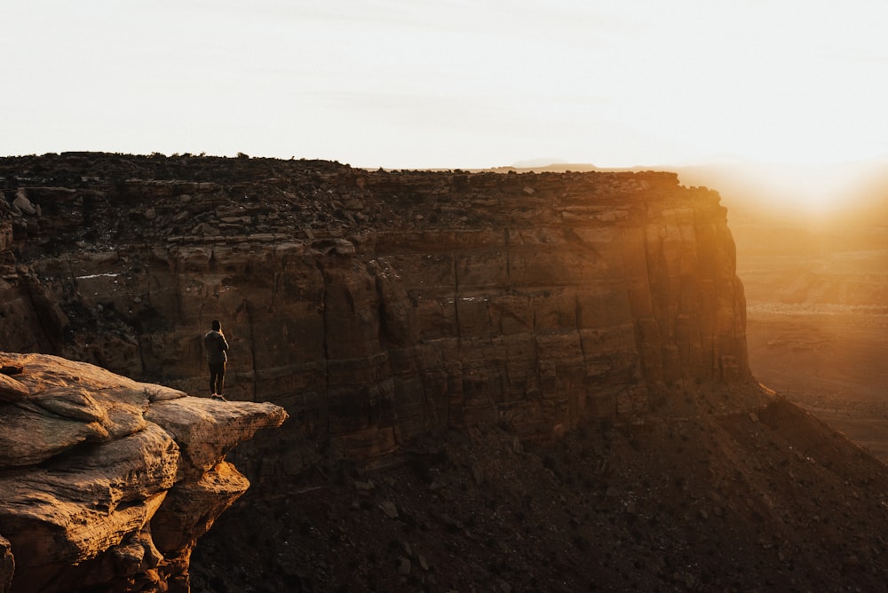 person standing on cliff at daytime