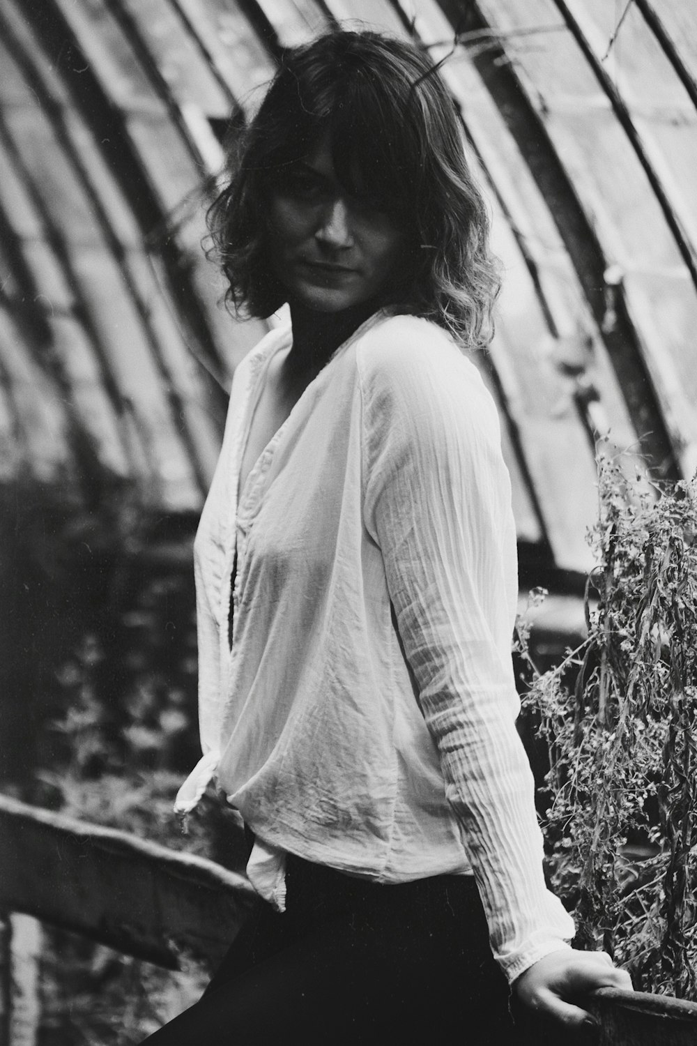 grayscale photo of woman leaning on fence