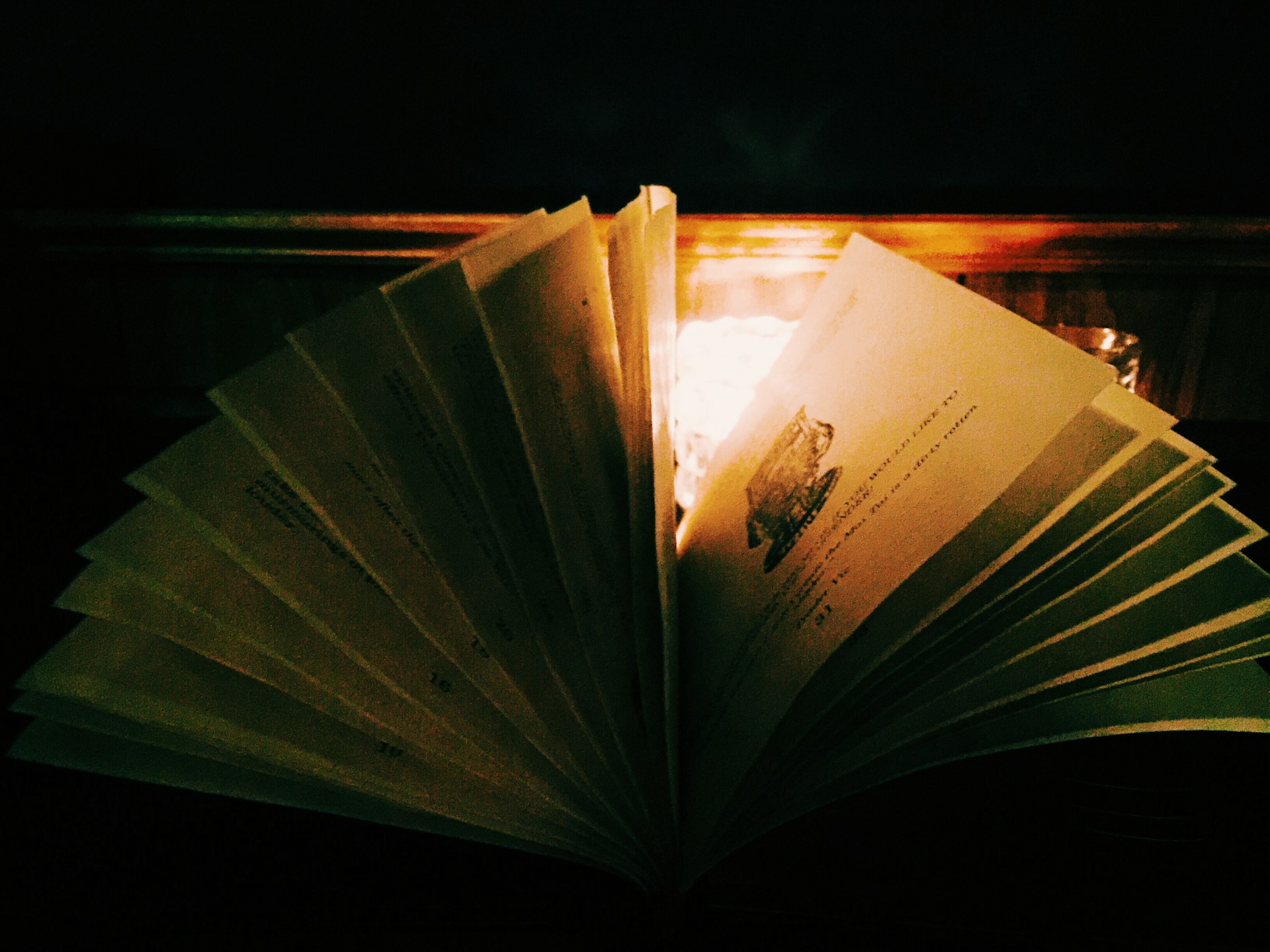 An ancient tome opened on a wooden table, with a flickering candle casting warm light over its pages.