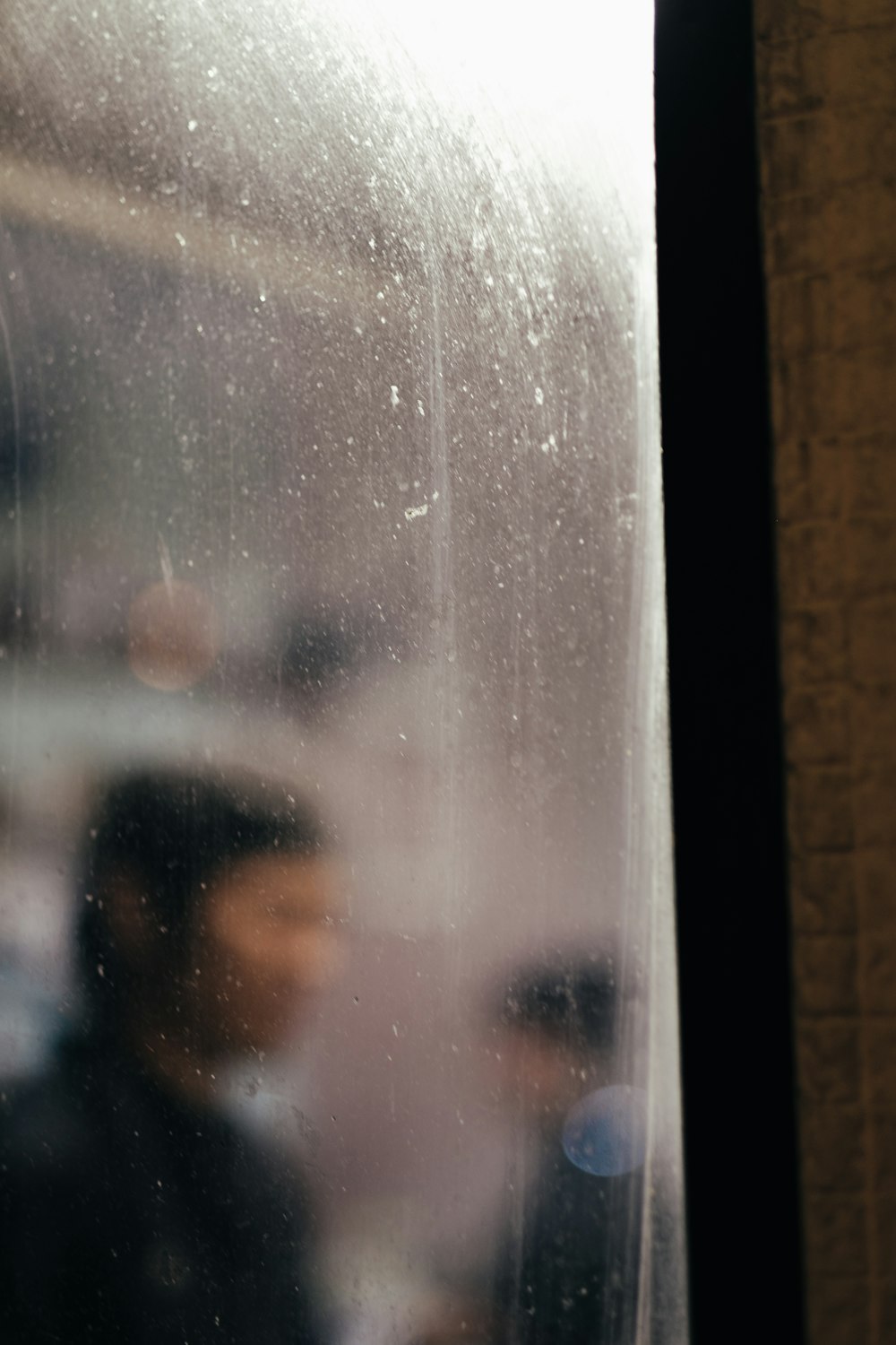 person in black shirt standing behind glass panel