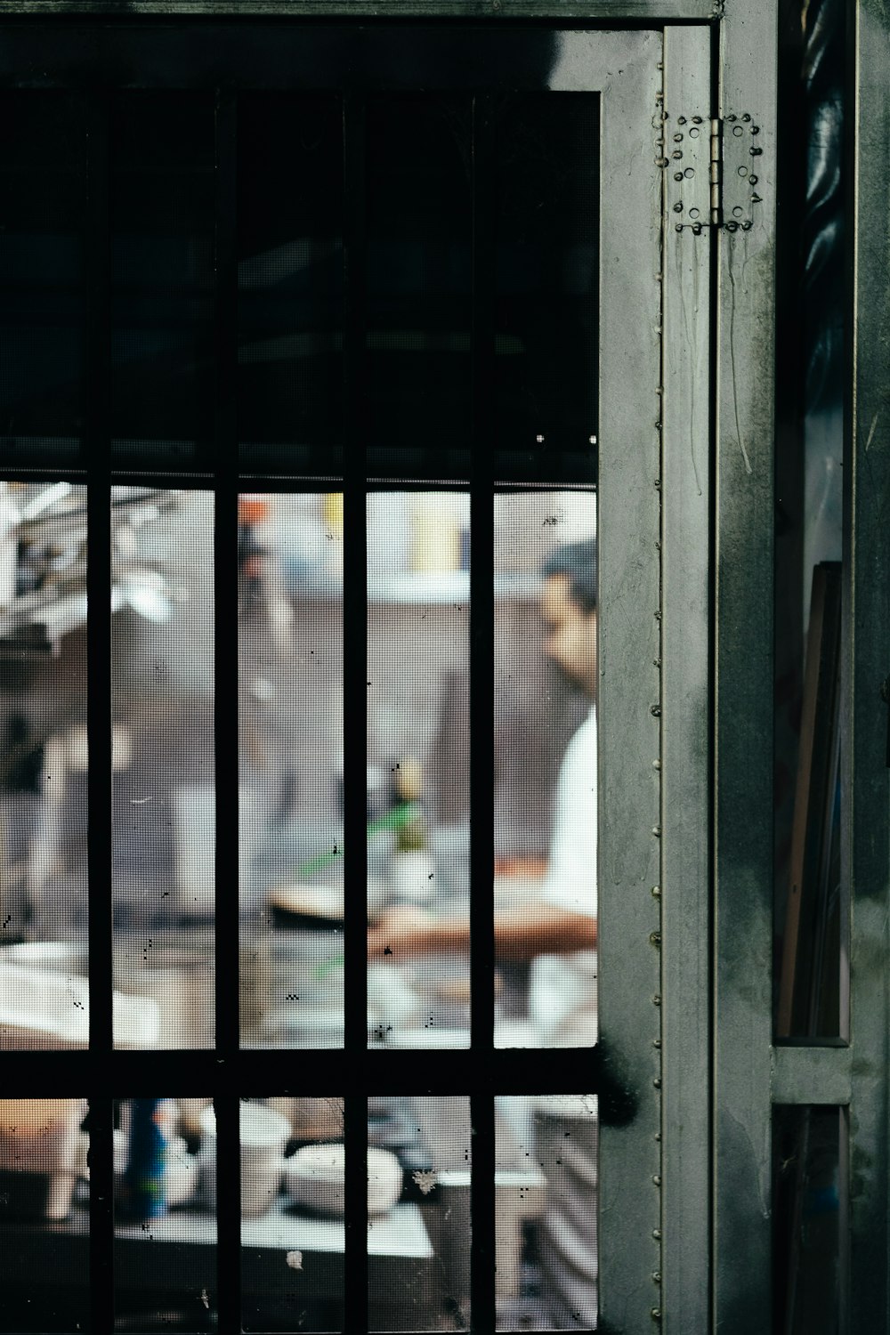 a man standing in a kitchen behind bars