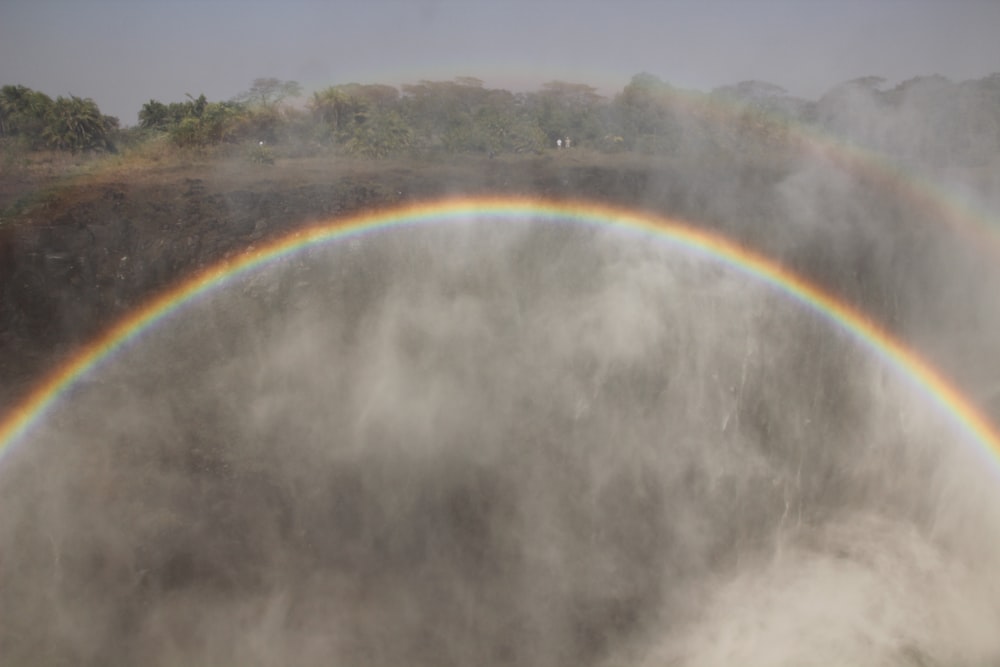 a double rainbow over a waterfall in the middle of the day