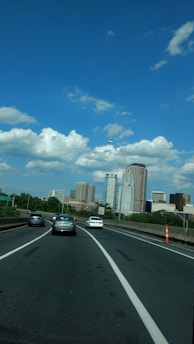 A map with a car moving from one city to another under clear skies.