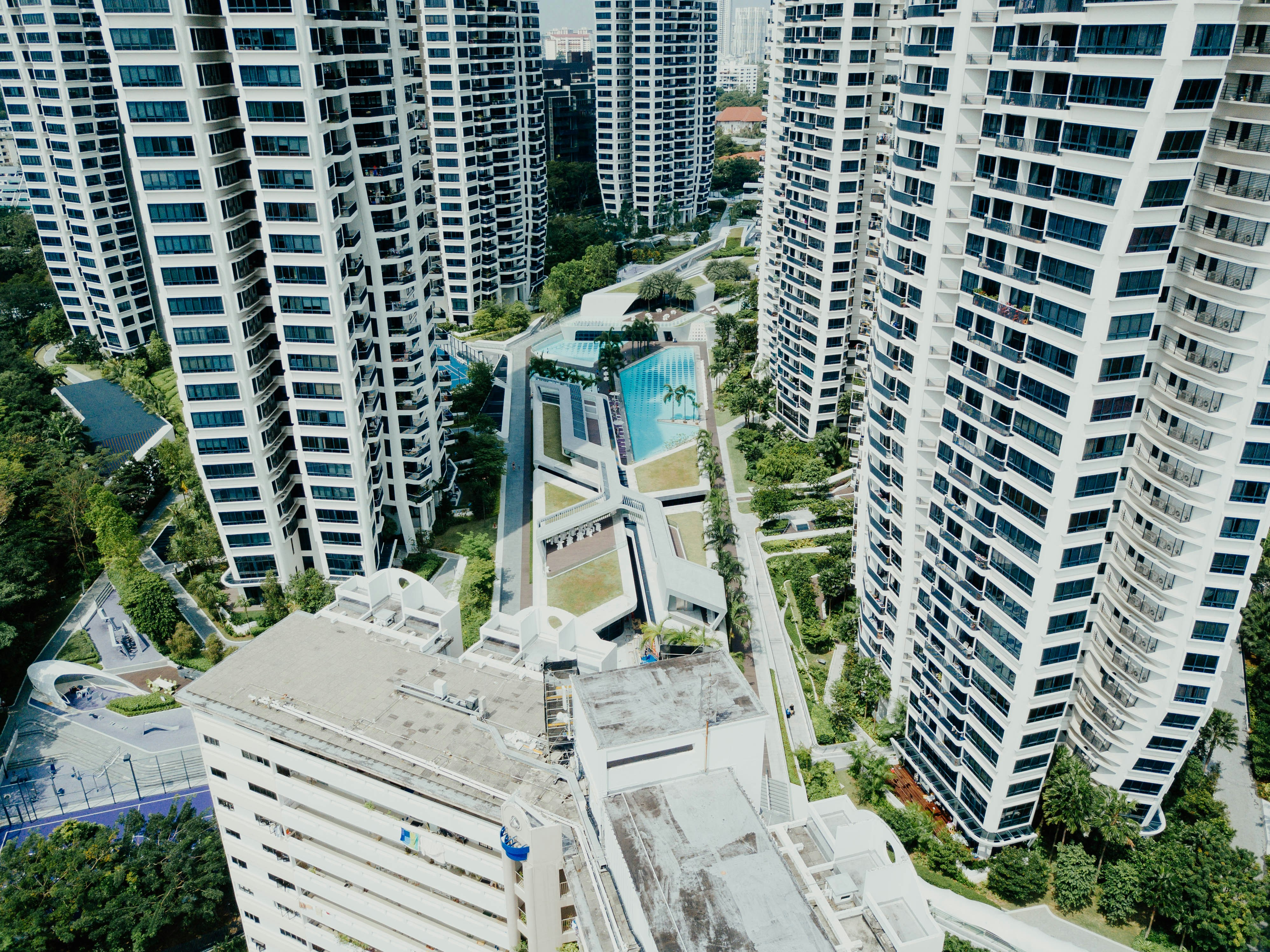 An aerial view of a modern apartment complex with a large, well-maintained dog park in the center, featuring play structures and green space - apartment complex pet friendly