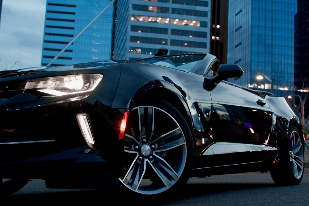 Coupé cabriolet noir garé près d’un immeuble de grande hauteur