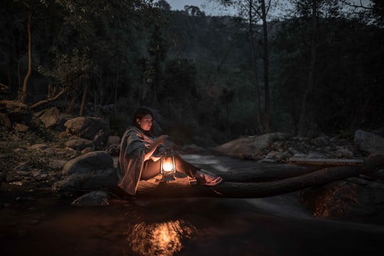 woman sitting on log carrying kerosene lamp in Chamba India