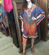 A customer happily trying on a custom-made Moroccan kaftan in a bright, welcoming shop.